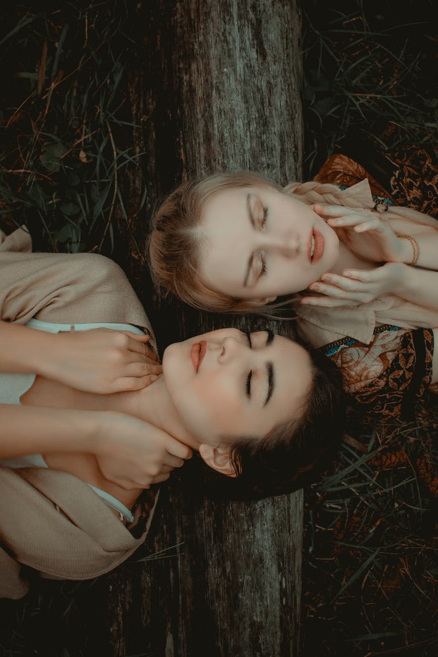 photo of two women lying on grass